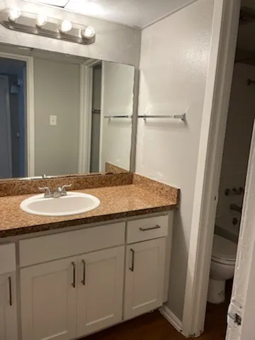 Vanity with white shaker-style cabinetry, granite-look countertop, and an undermount sink