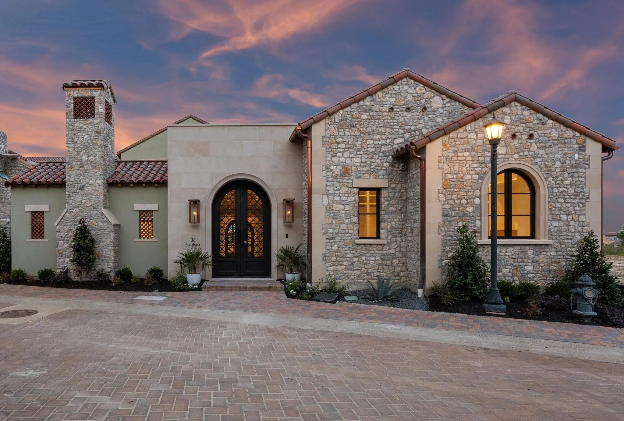 View of front facade with french doors, stone siding, a tiled roof, stucco siding, and a chimney