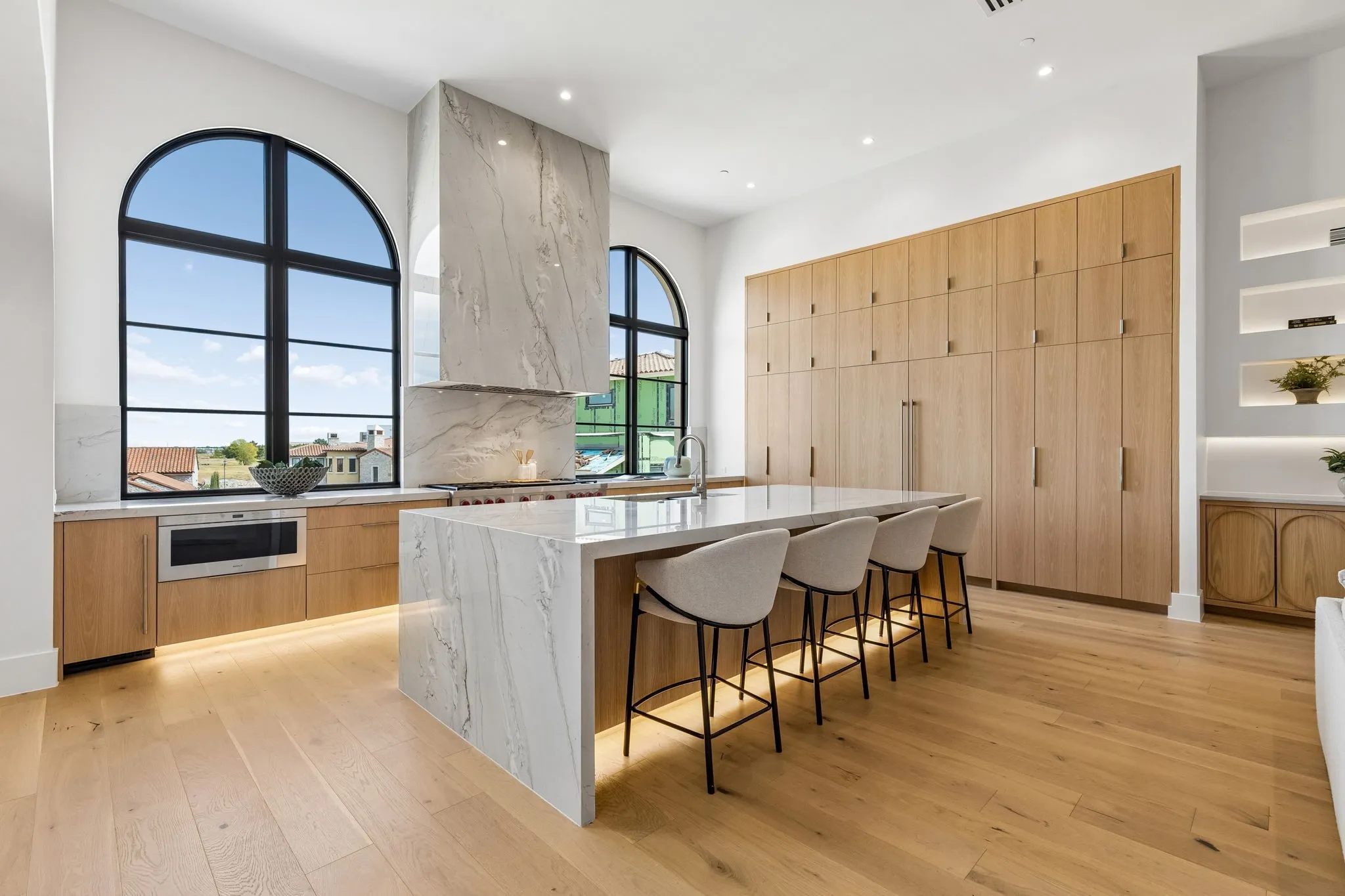 Kitchen featuring modern built-in cabinets, White oak floors, Wolf & SubZero appliances, light stone countertops, and recessed lighting