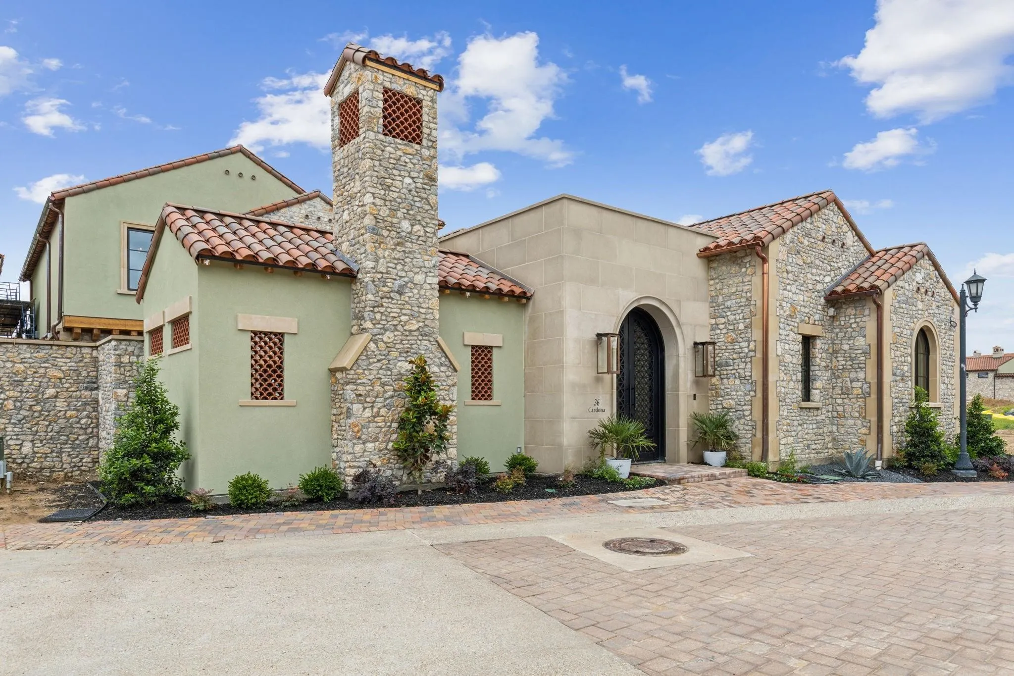 Mediterranean / spanish-style home with a tiled roof, stucco siding, a chimney, and stone siding