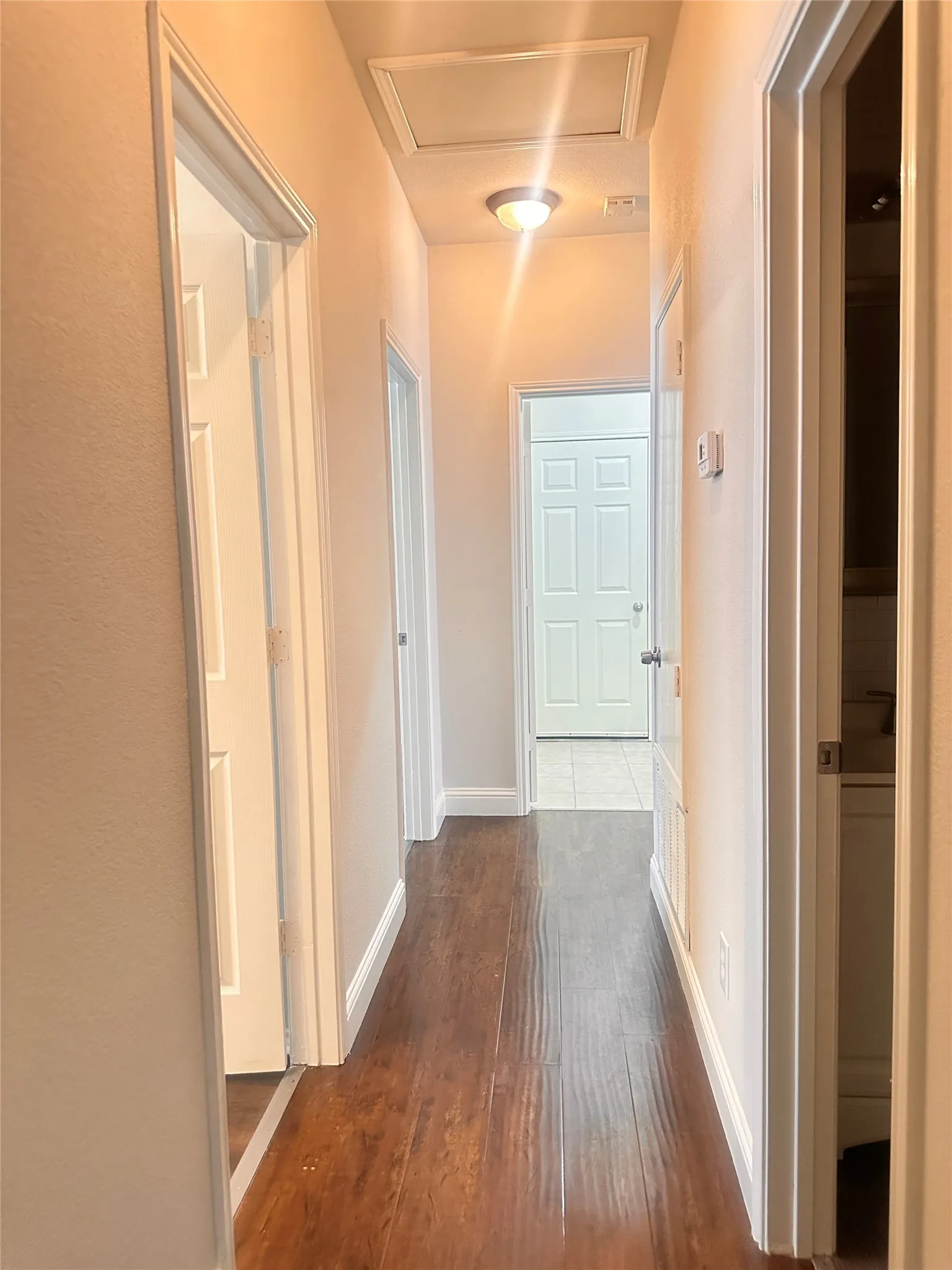 Hall with dark wood-type flooring and baseboards