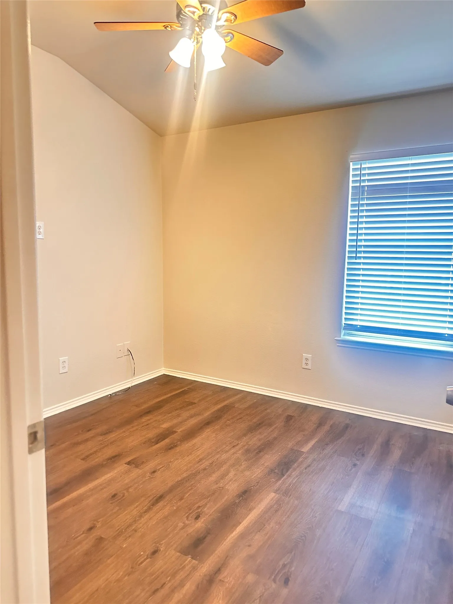 Spare room featuring dark wood finished floors and ceiling fan