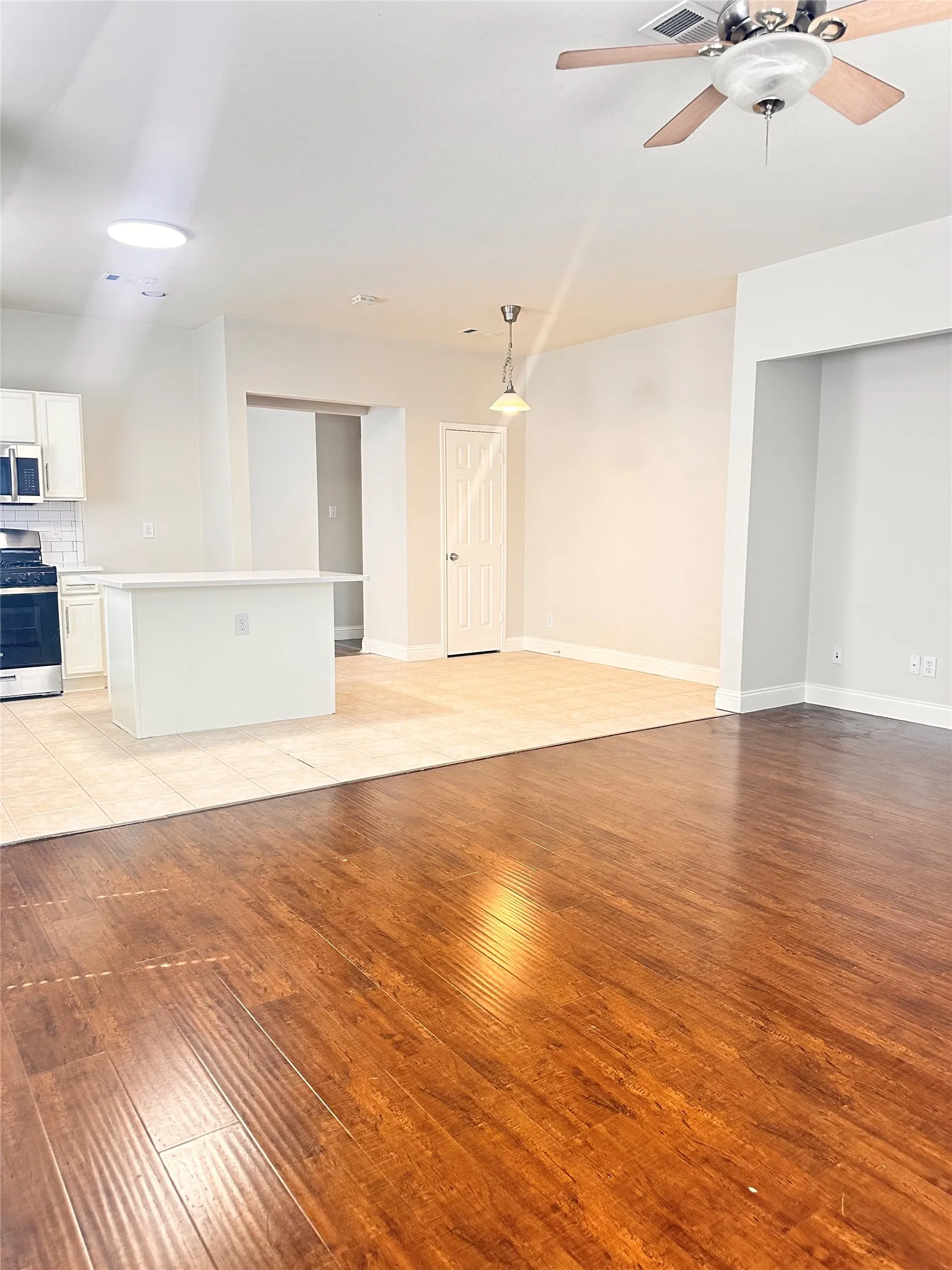 Unfurnished living room featuring light wood-style floors and a ceiling fan