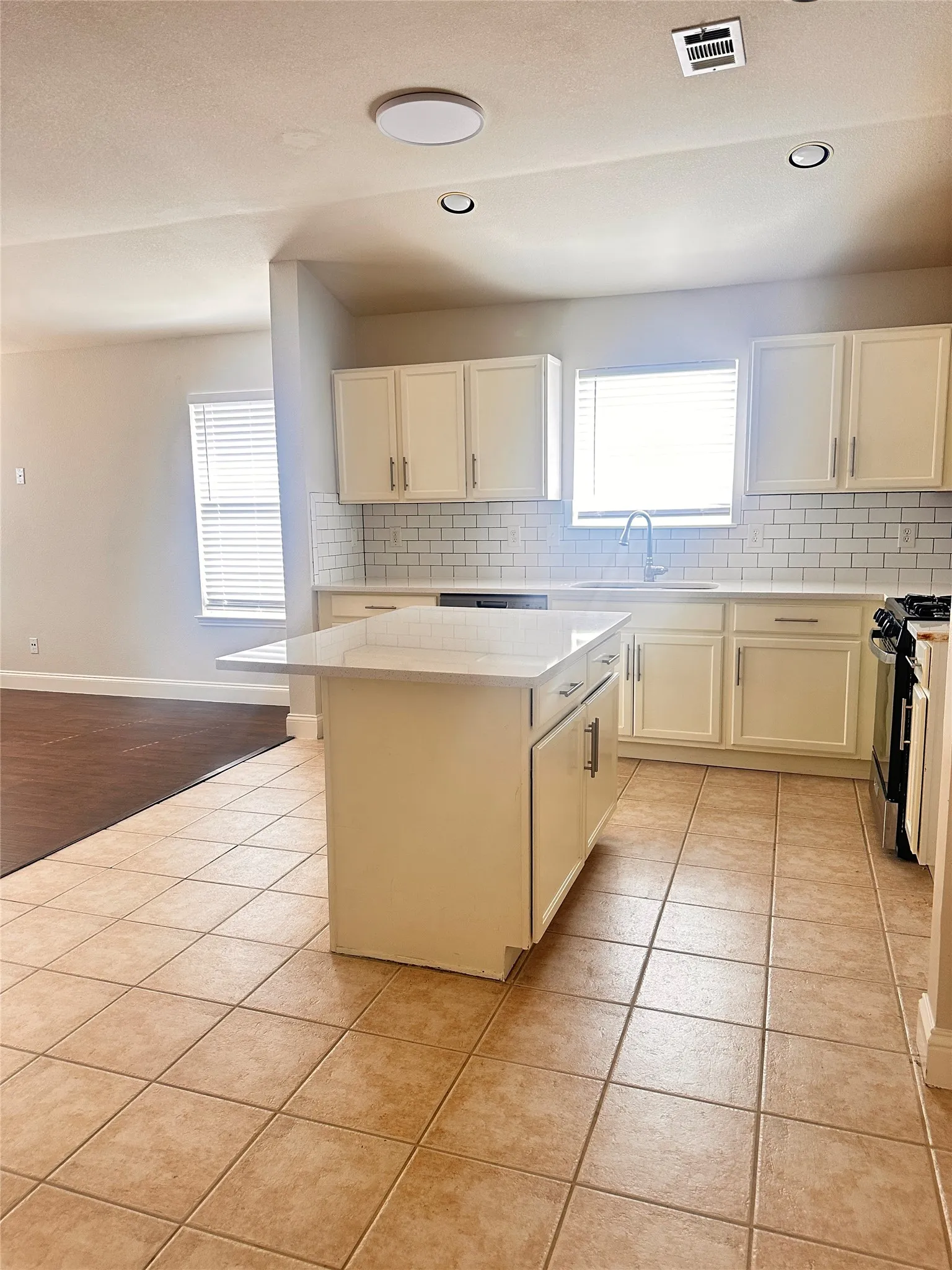 Kitchen with backsplash, white cabinetry, gas stove, and recessed lighting