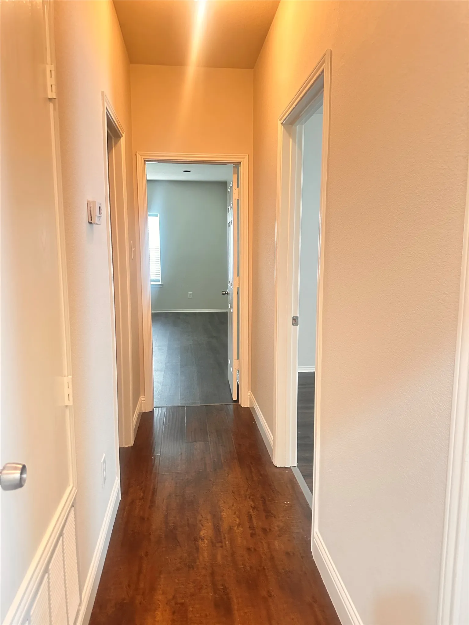 Hallway featuring dark wood finished floors and baseboards