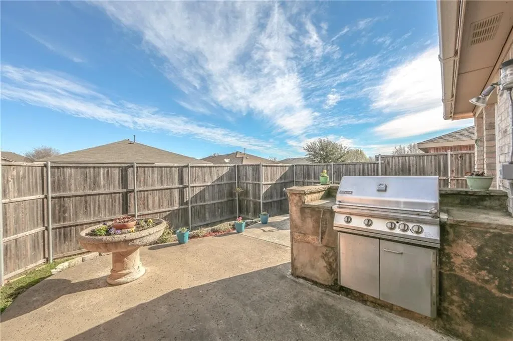 Fenced backyard with a patio area and exterior kitchen