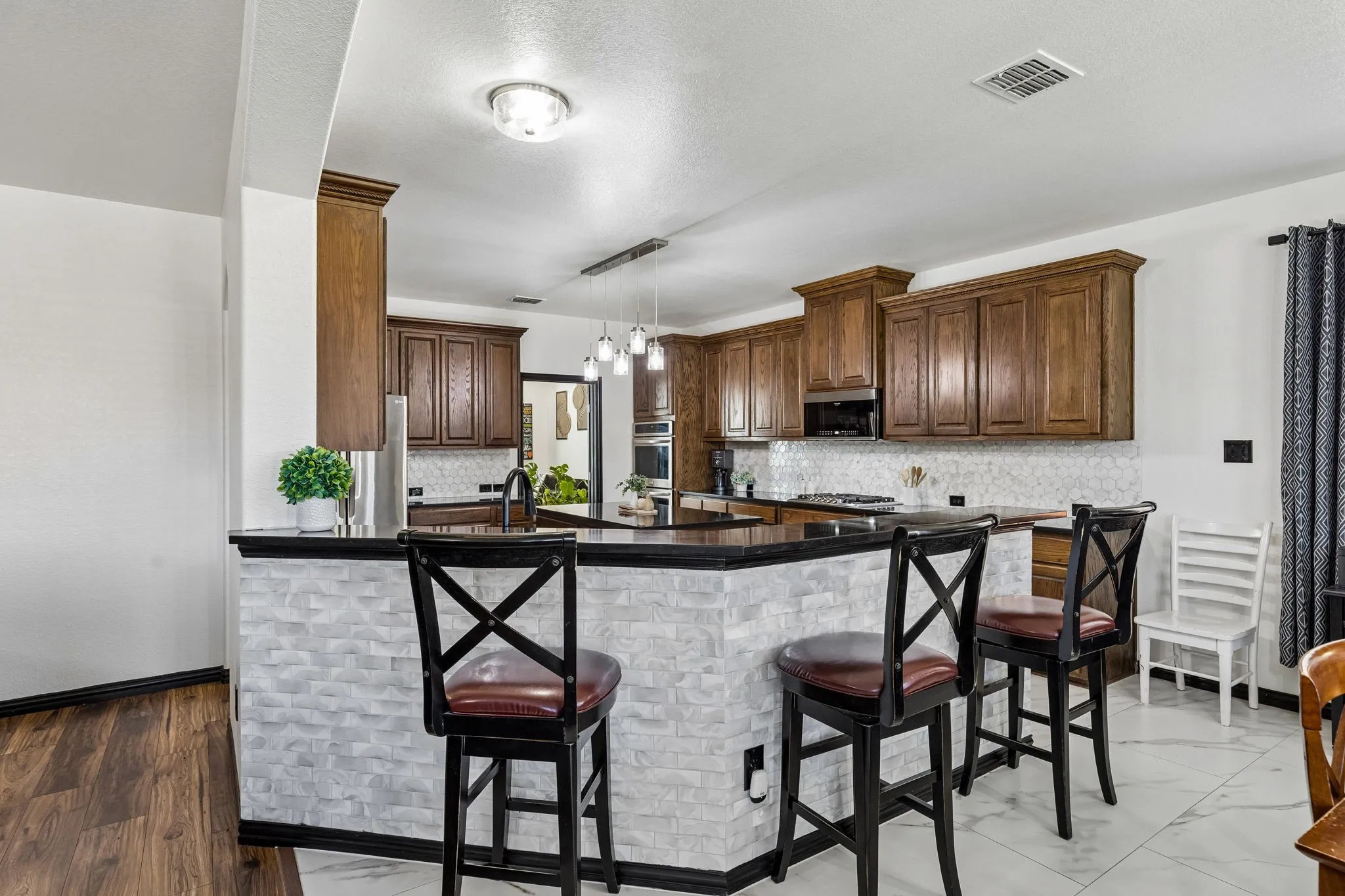 Convenient Casual Dining – The extended breakfast bar offers additional seating and serving space, with a stylish textured tile accent beneath the counter. Its open design keeps the kitchen connected to the breakfast area and family room.