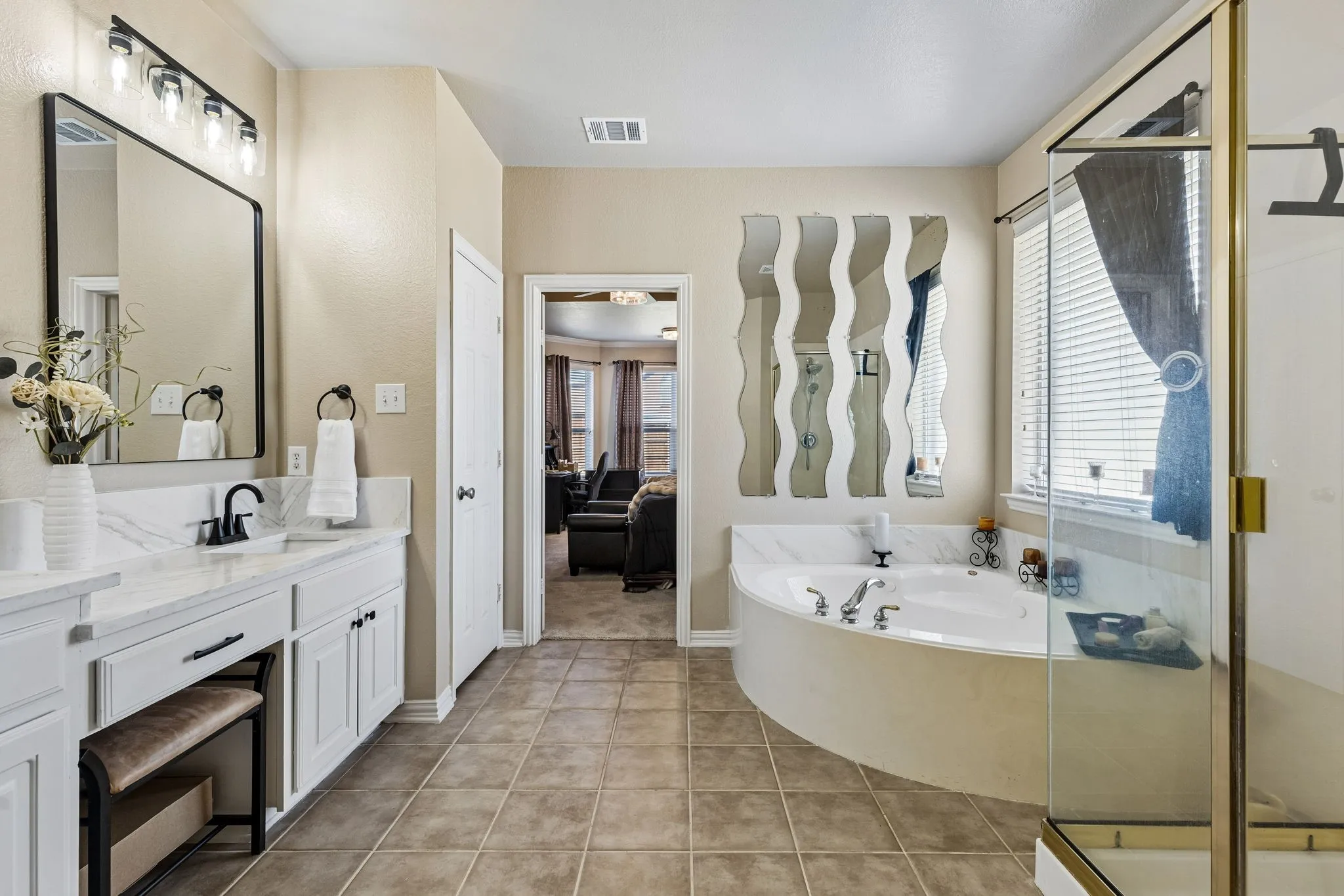 A Relaxing Place to Unwind – Enjoy a jetted garden tub with an updated quartz surround, positioned beneath a window for natural light. The separate glass-enclosed shower and spacious bathroom layout offer comfort and convenience.