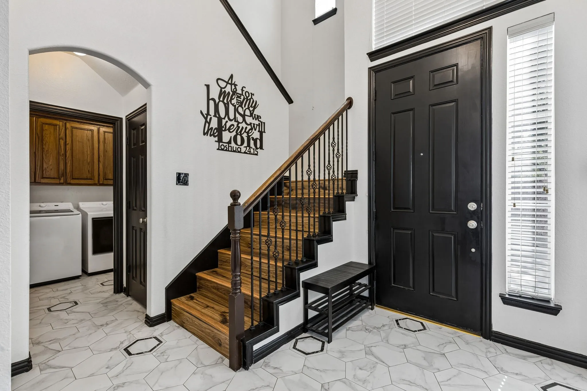 A Welcoming Two-Story Entry – Soaring ceilings create an airy first impression, while the staircase features wood-look treads and decorative iron balusters. The nearby laundry room adds everyday convenience just steps from the front door.