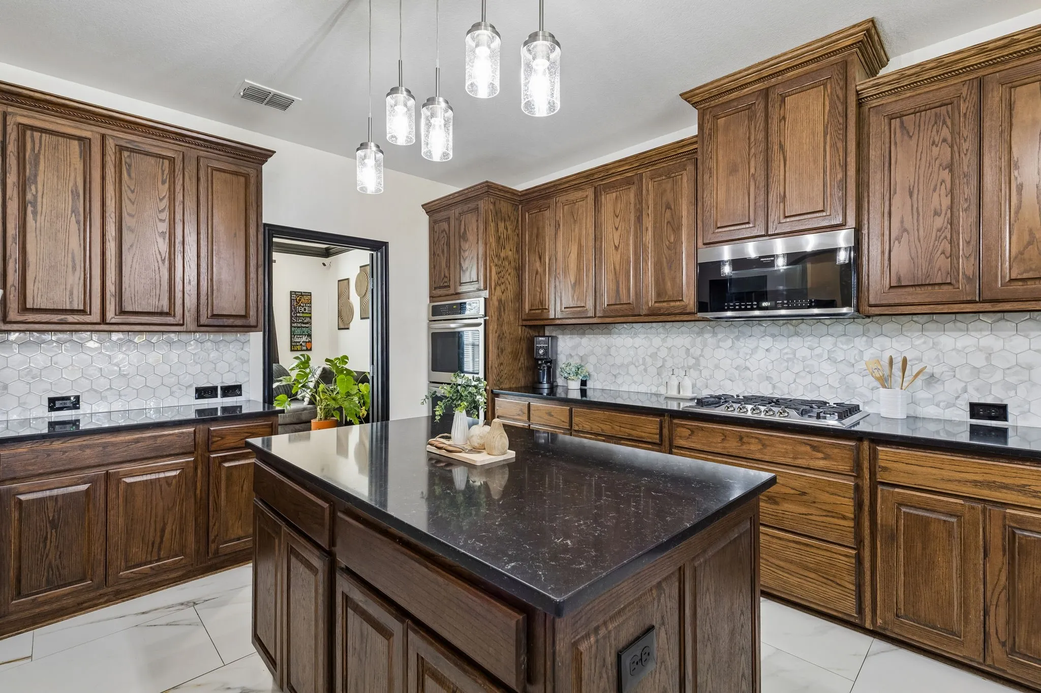 Equipped for Cooking – Stainless steel double ovens, a five-burner gas cooktop, and extensive cabinetry create a highly functional cooking space. Updated pendant lighting over the island adds a polished finishing touch.