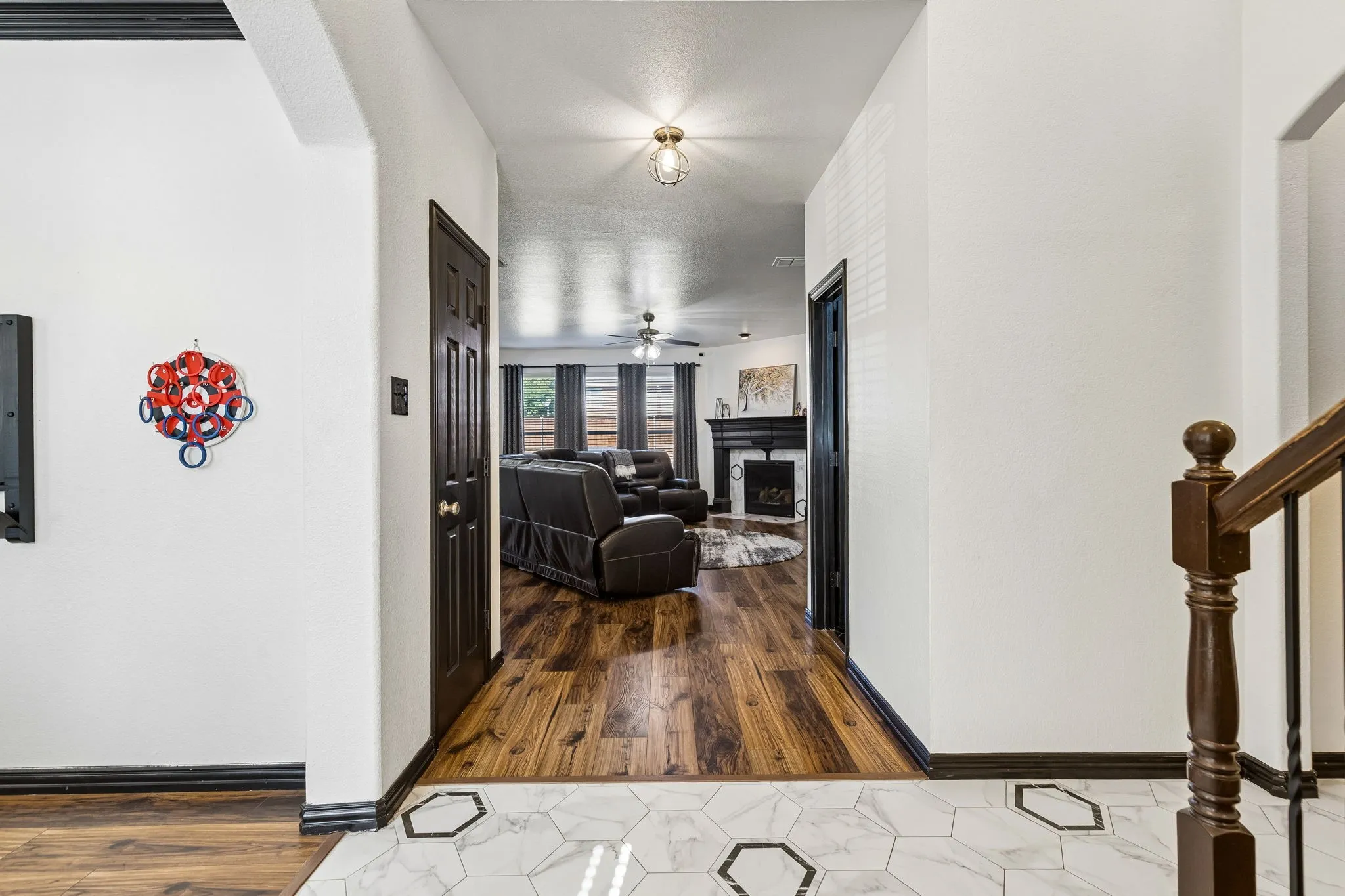 Updated Finishes Make a Statement – The entry introduces the home's distinctive style with decorative hexagon tile flooring, contrasting black trim and doors, and a seamless transition into the spacious family room with waterproof laminate flooring.