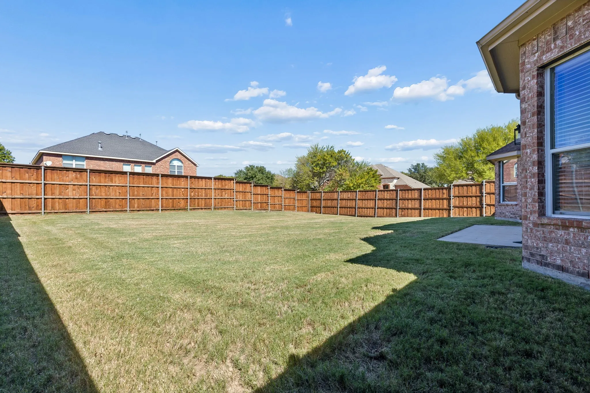 Outdoor Space to Make Your Own – With a generous stretch of level lawn and a wood privacy fence, this backyard provides a wonderful blank canvas for outdoor living. Imagine adding a patio extension, grilling area, or inviting gathering space for evenings outdoors.
