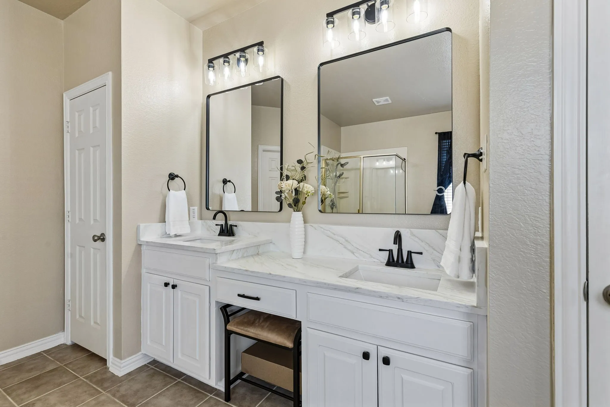 Beautifully Updated Dual Vanity – Fresh white cabinetry, quartz countertops with undermount sinks, matte black faucets, and coordinating framed mirrors give the primary bath a refreshed look. A dedicated seated vanity area adds convenience to the daily routine.