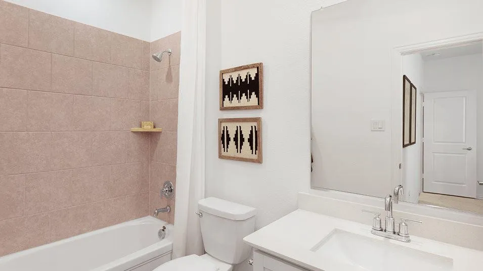 Full-height tile bath surround, chrome plumbing fixtures, white porcelain bathtub, and white vanity with an integrated sink