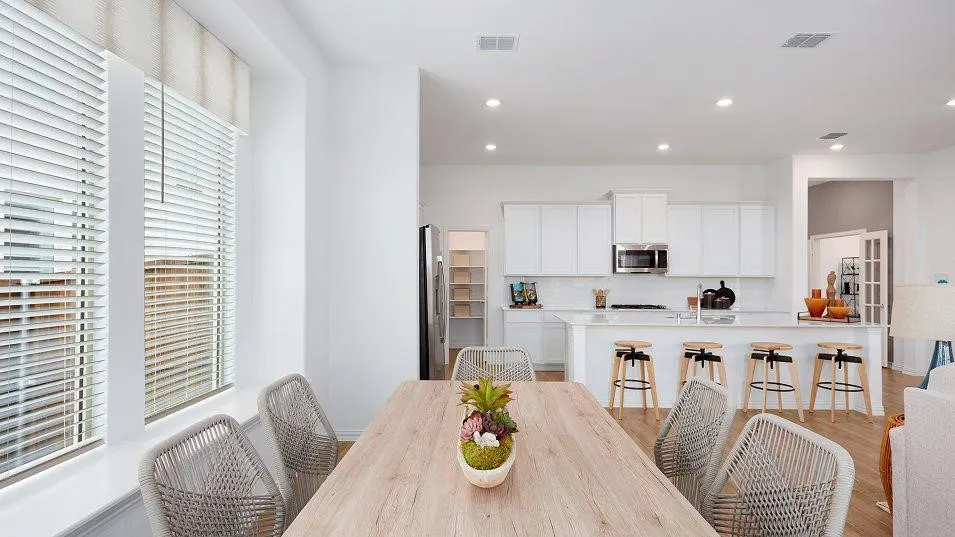 White kitchen cabinetry with stainless steel appliances, a center island with seating, a tile backsplash, and recessed lighting