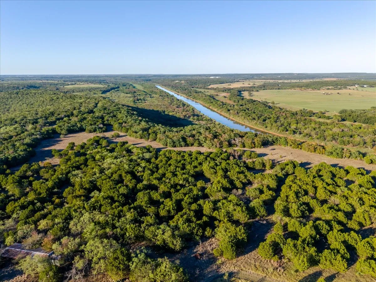 Expansive undeveloped land featuring a linear waterway and dense tree coverage