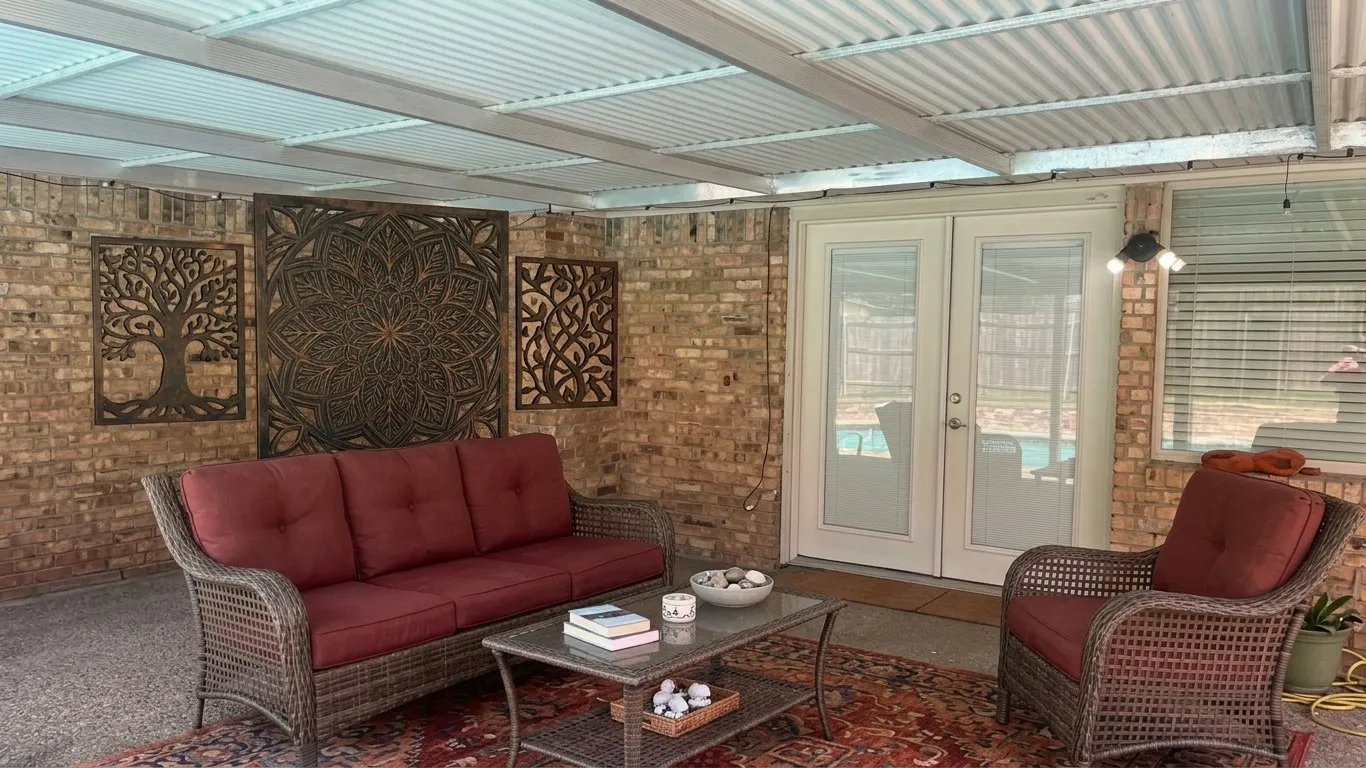Staged AI furniture;  Covered patio featuring a corrugated translucent ceiling, exposed brick wall, and French patio doors.