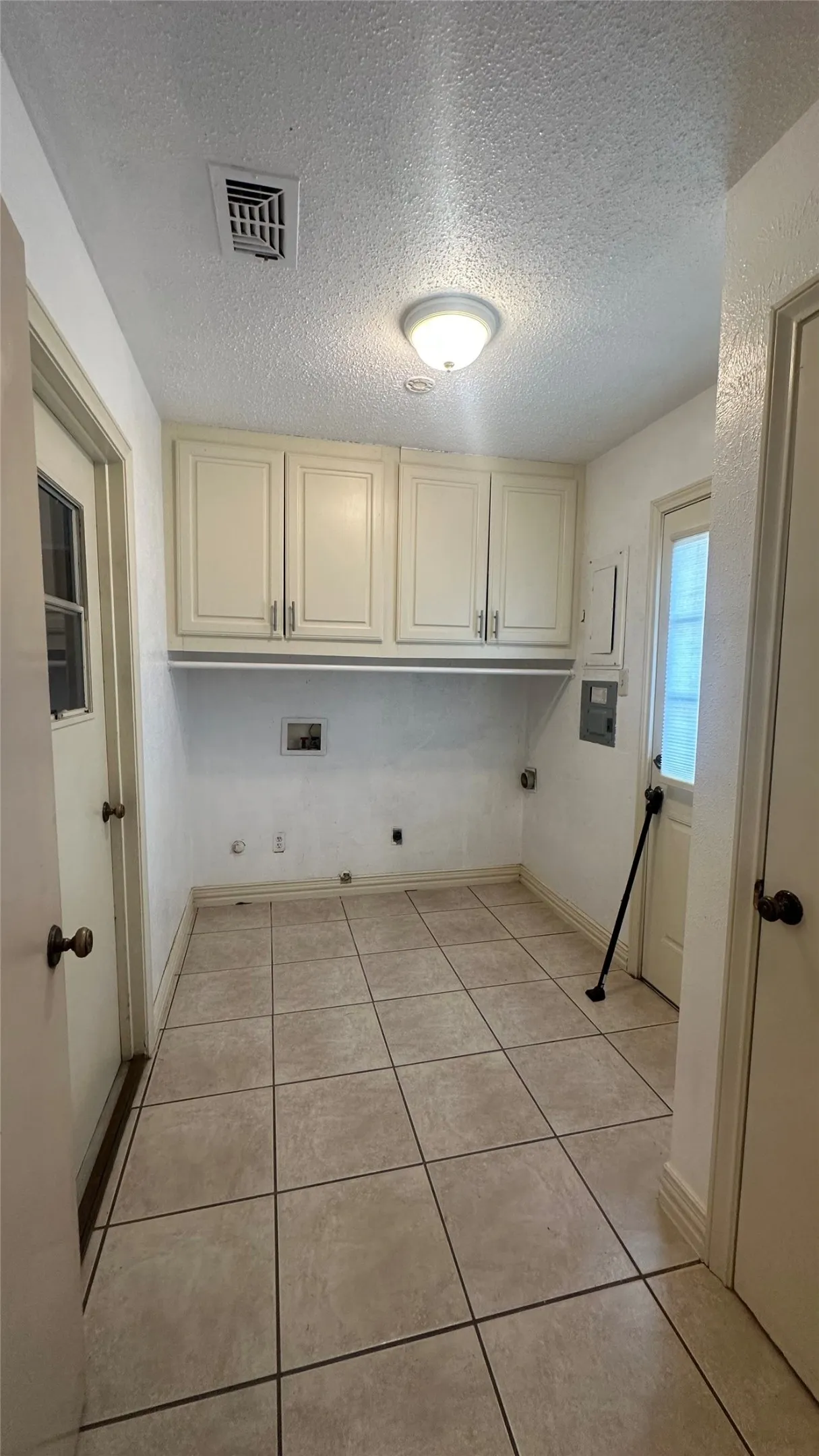 Tile flooring, ceiling-mounted light fixture, upper cabinetry, utility hookups, and exterior-access door to pool/yard and door to access garage.  Located just off the kitchen, separate room.