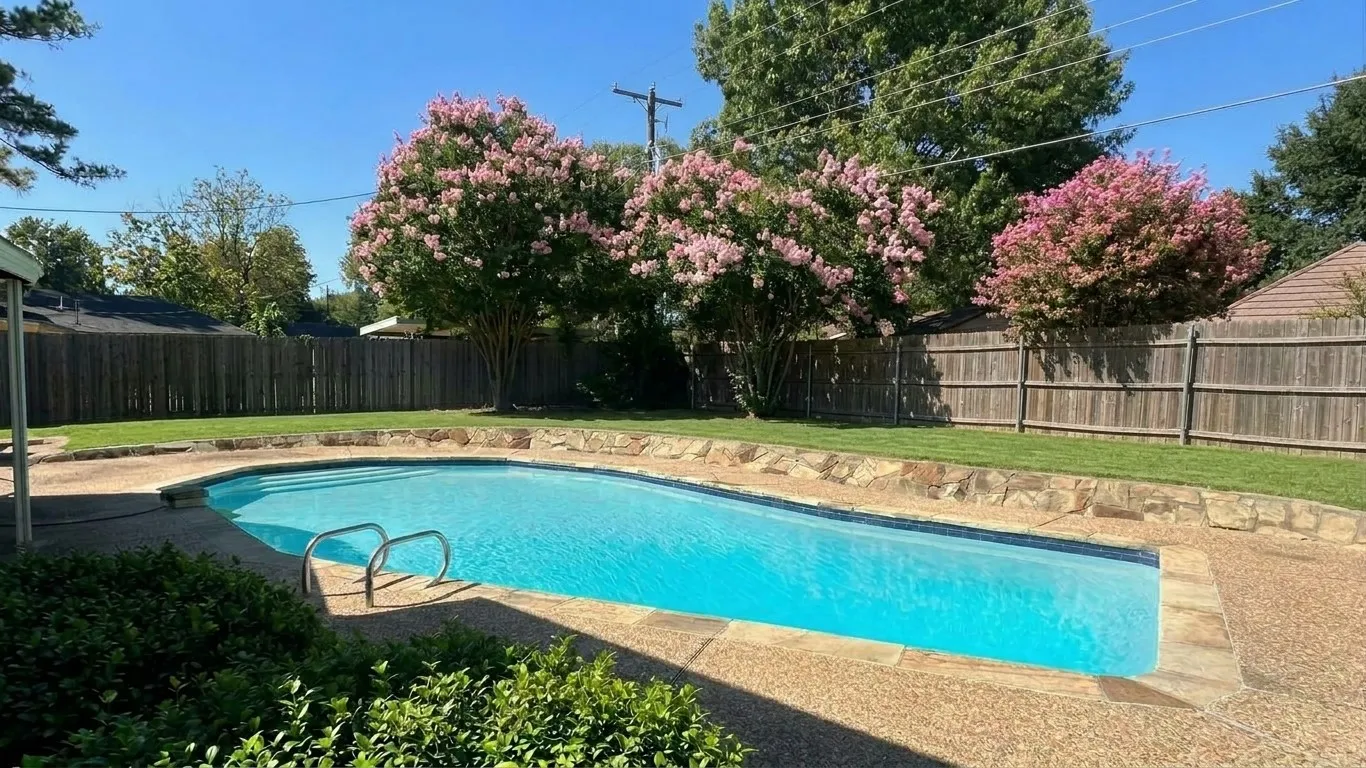 In-ground swimming pool with surrounding concrete patio, grassy areas, landscape & nice storage building.