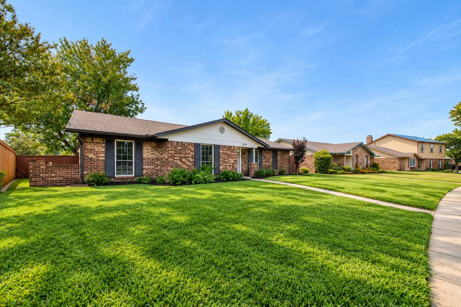 Brick exterior with dark shutters, front landscaping, and a well-maintained lawn