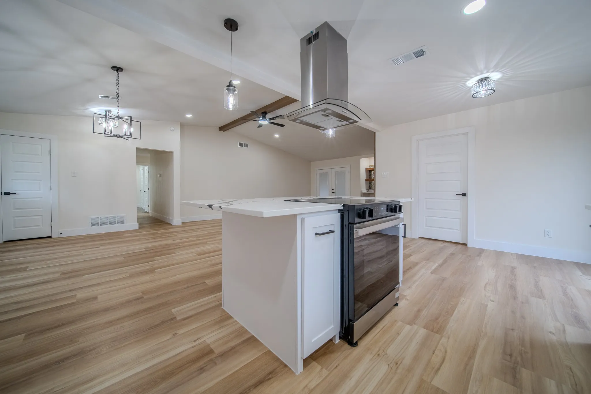 Open-concept kitchen featuring an island, stainless steel range with range hood, and wood-finish flooring