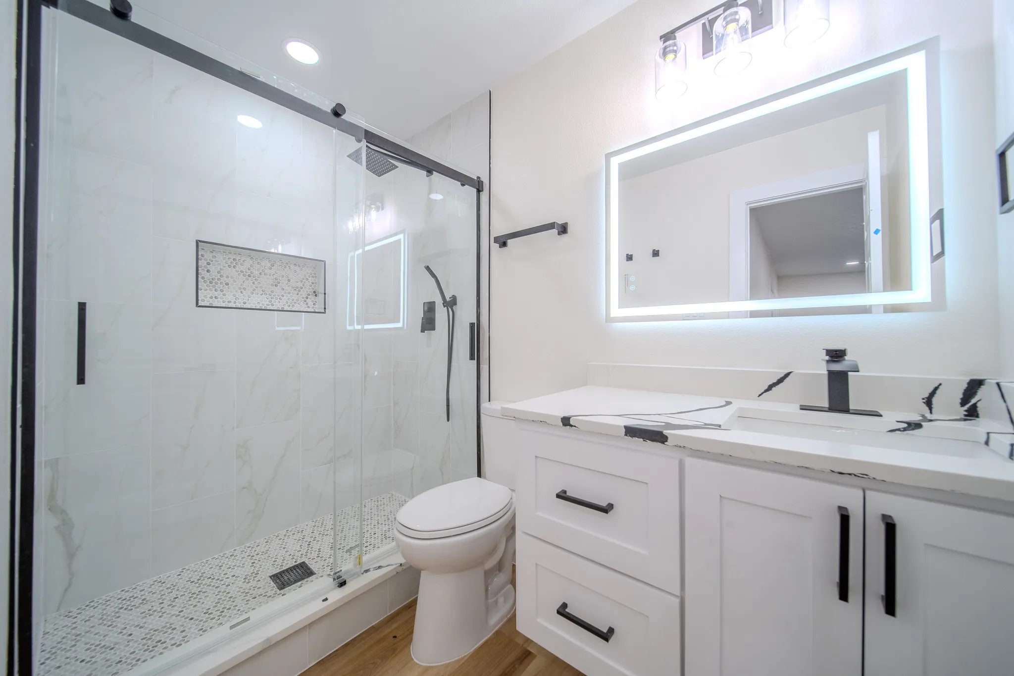 White vanity with black hardware, a rectangular undermount sink, and a black faucet