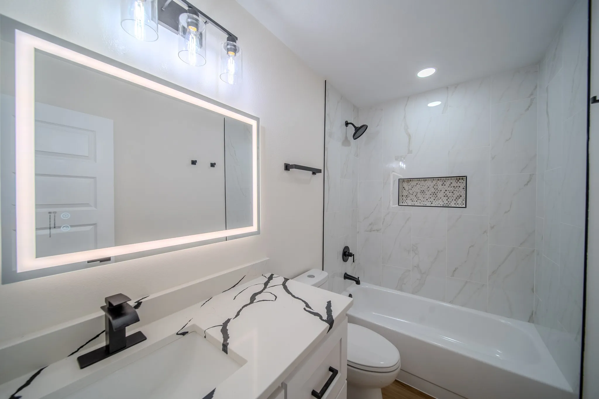 Bathroom featuring a white vanity with a black veined countertop, black faucet, and rectangular undermount sink
