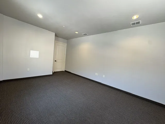 Light gray painted walls, recessed lighting, and patterned dark gray carpeting