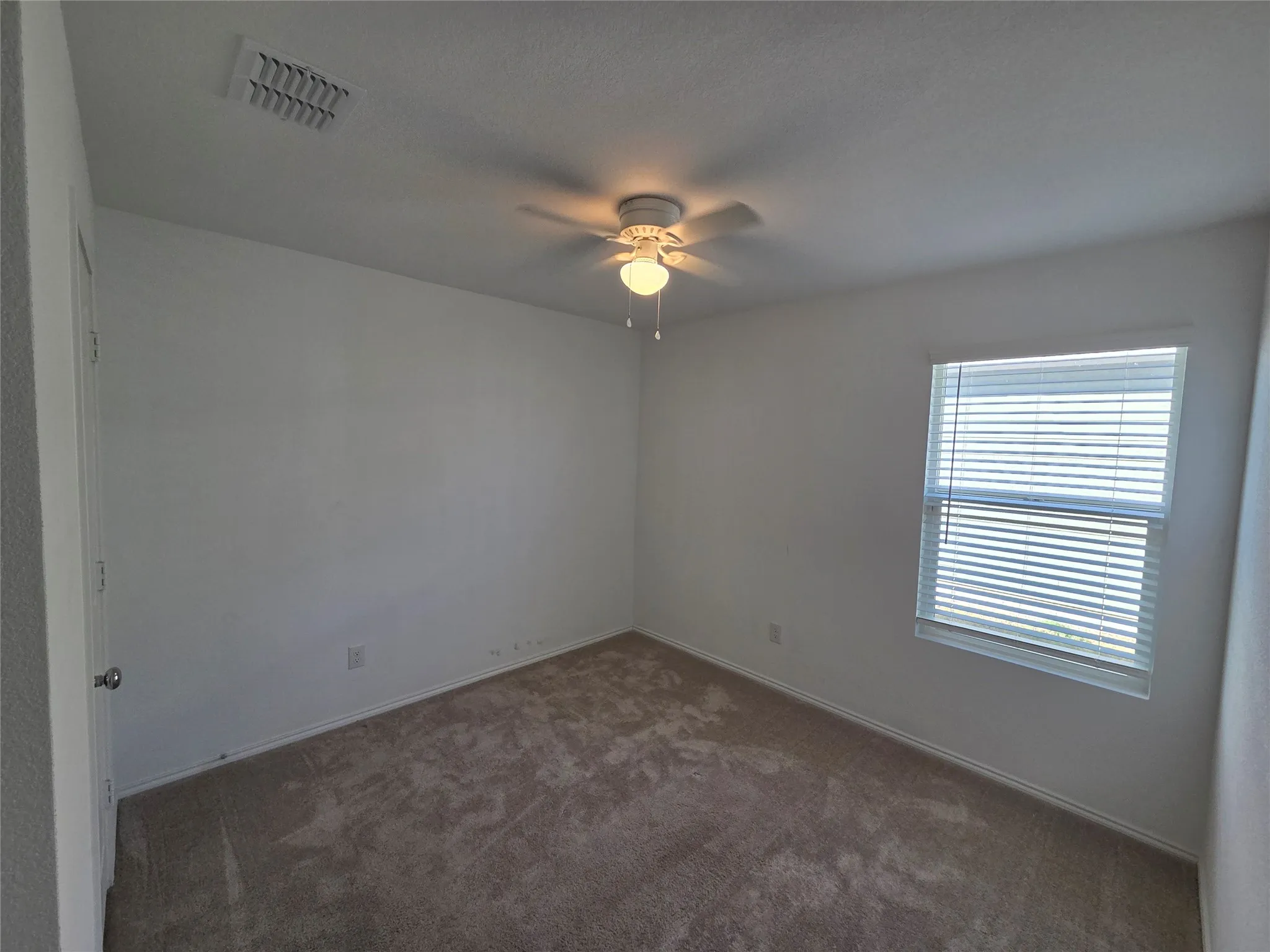 Neutral wall color, carpet flooring, window with blinds, and ceiling fan with integrated lighting