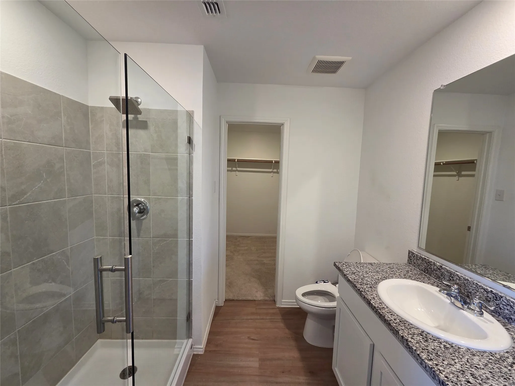 Walk-in shower with clear glass enclosure and tile surround