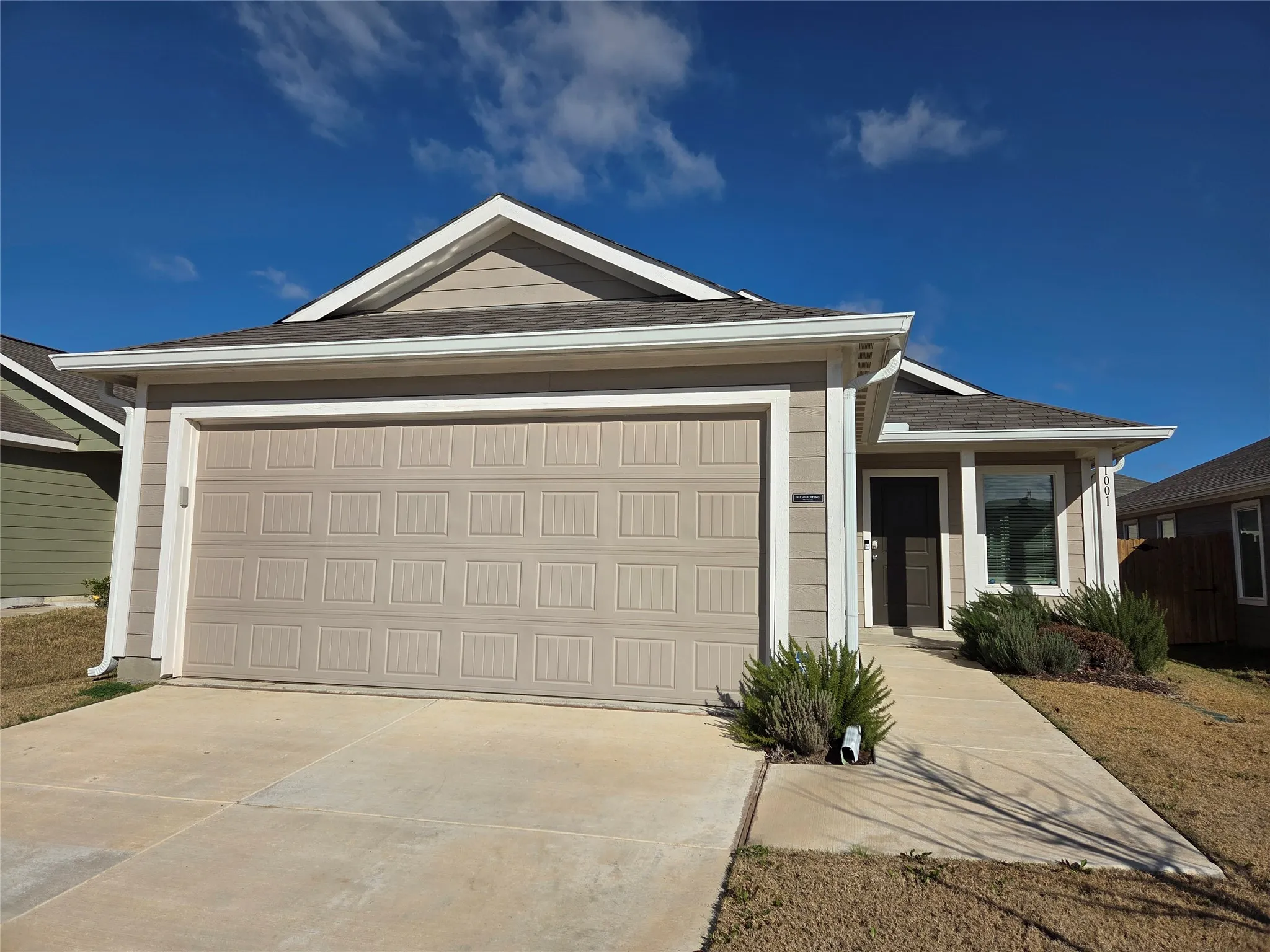 Contemporary single-story residence featuring composite siding, an attached garage, a paved driveway, and a concrete walkway