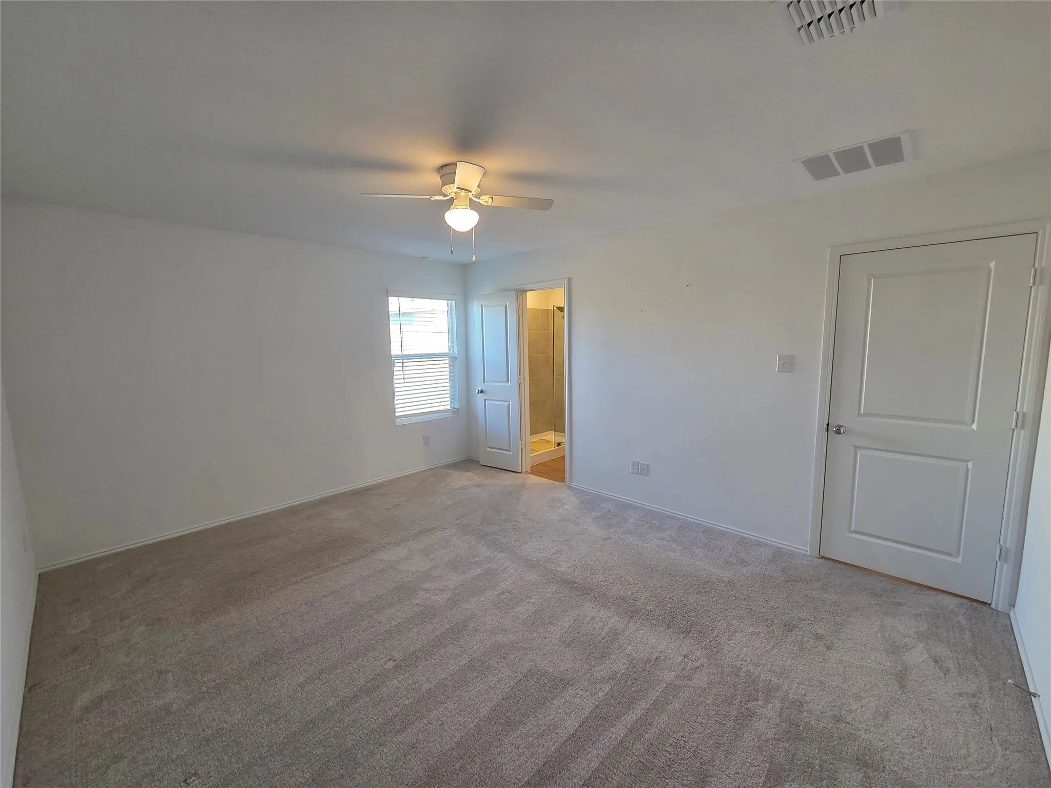 Spacious room with plush carpet, a ceiling fan, and a window with blinds