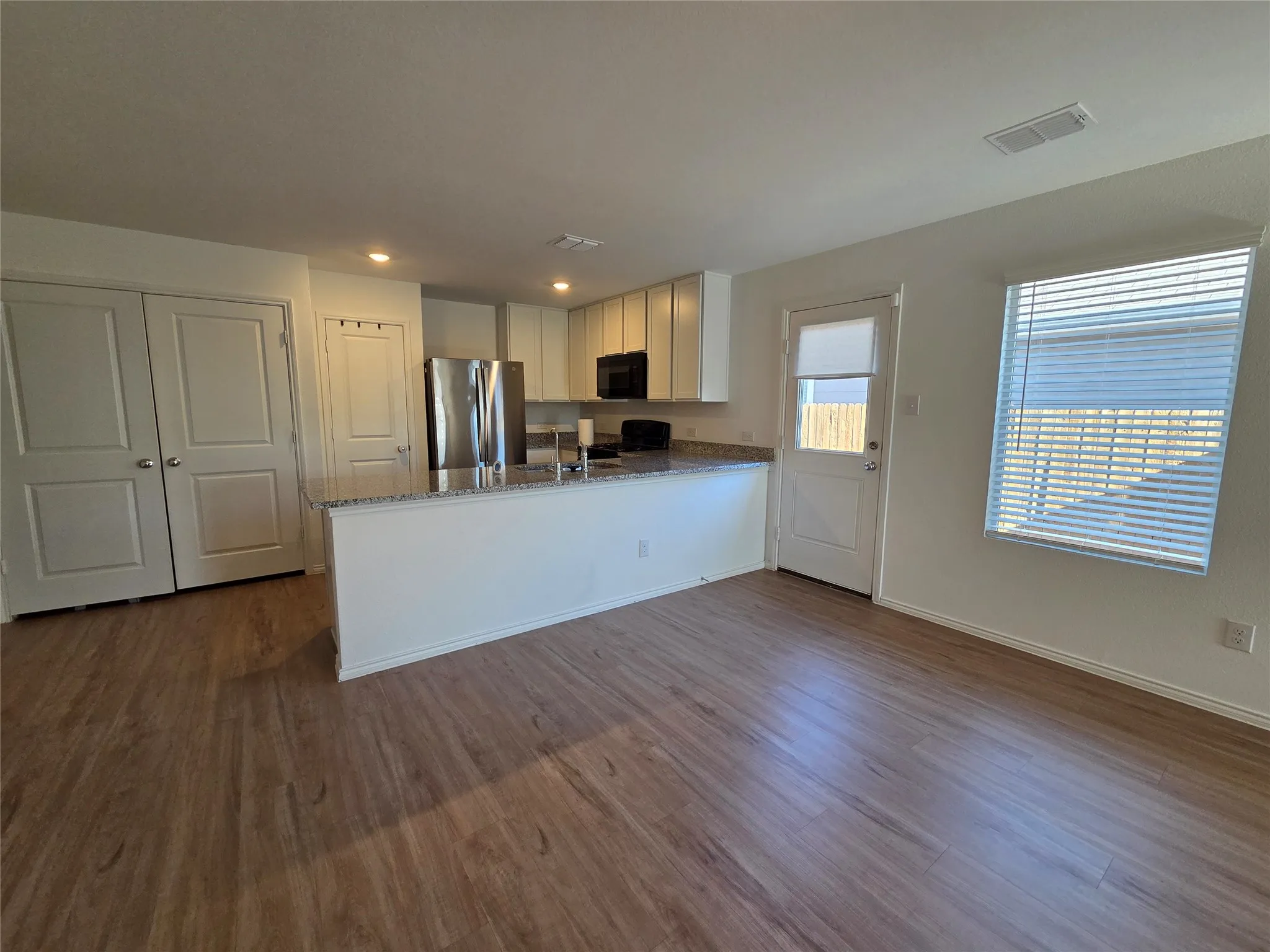 Open-concept layout with wood-finish flooring, recessed lighting, and a kitchen island featuring a light-toned countertop