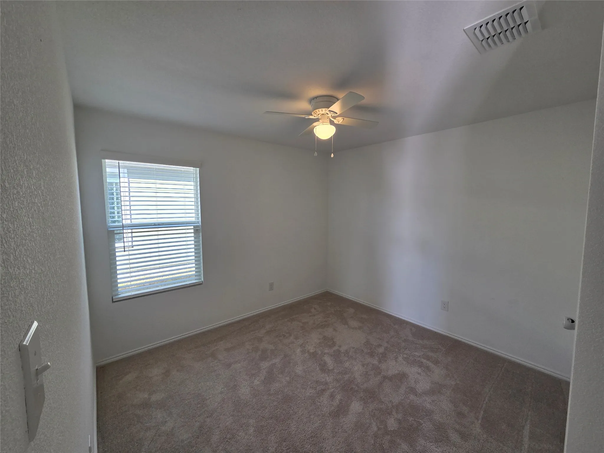 Neutral wall paint, carpeted flooring, window with blinds, and ceiling fan with integrated lighting