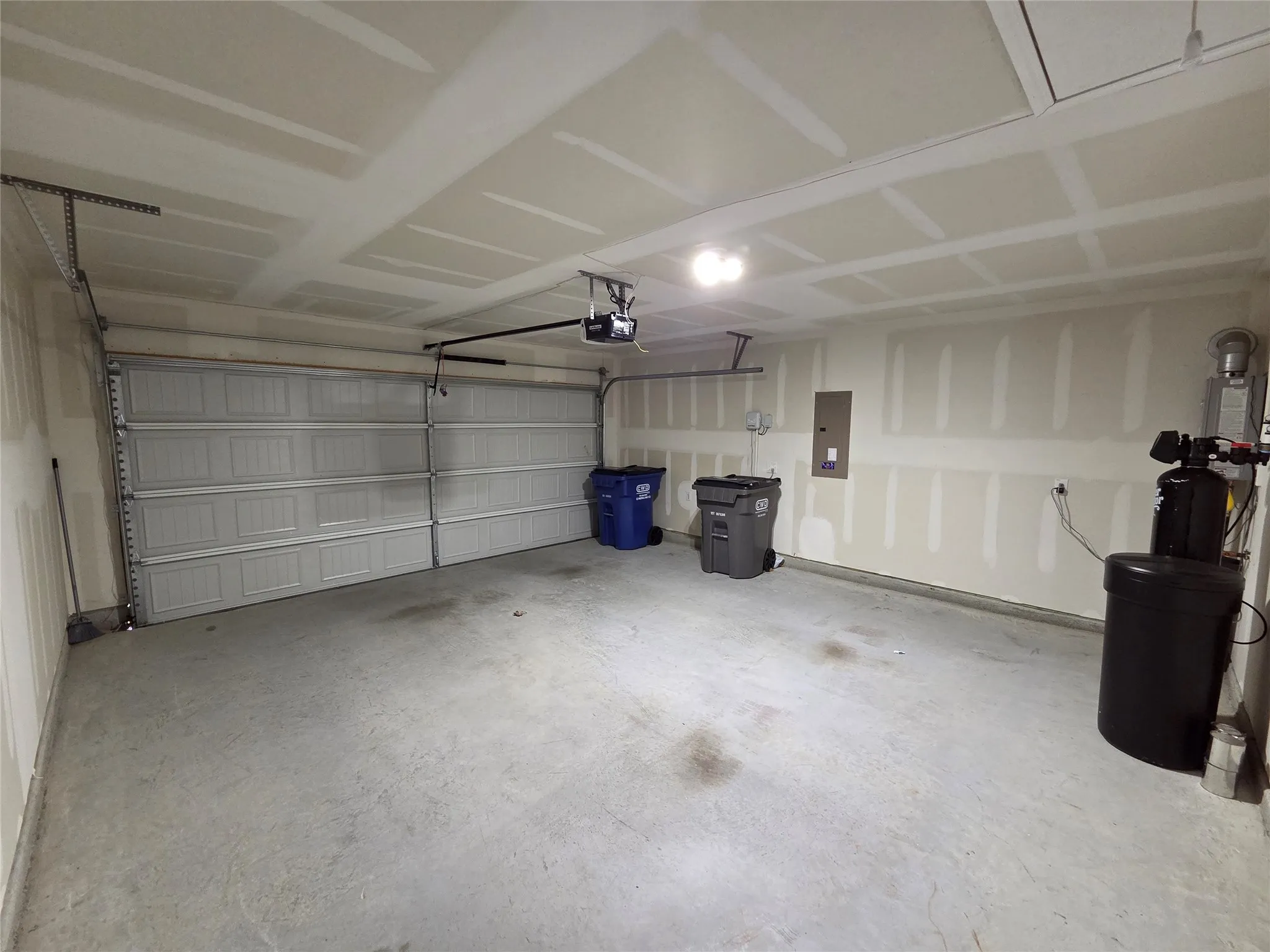 Attached garage with a panel garage door, overhead lighting, and exposed ceiling joists