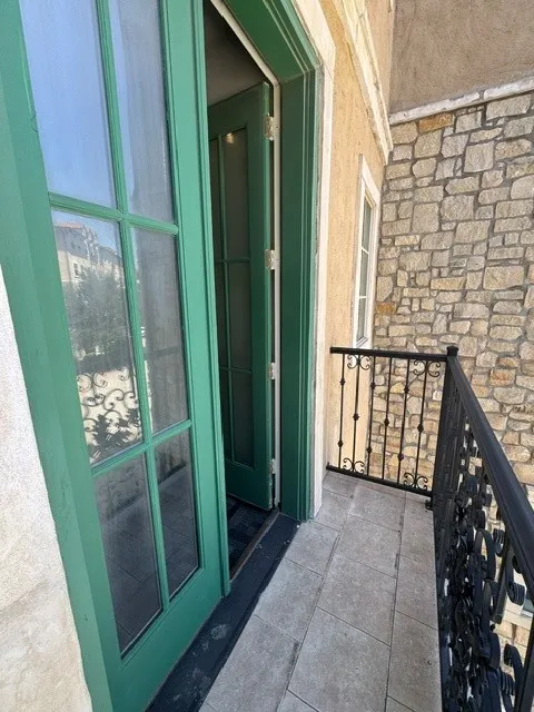 Balcony featuring tile flooring, decorative wrought iron railing, and a stone exterior wall