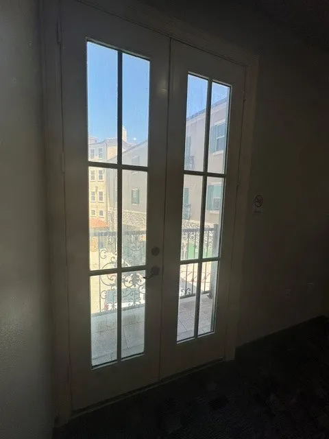 French doors featuring divided lites and an exterior balcony with an ornamental metal railing