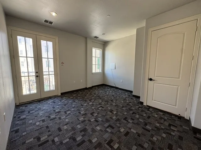 Patterned carpet flooring, French doors with glass panes, single pane window, recessed lighting, and a paneled interior door with matte black hardware