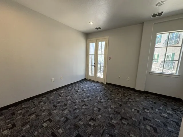Recessed lighting, patterned carpet flooring, and a window with exterior architectural details