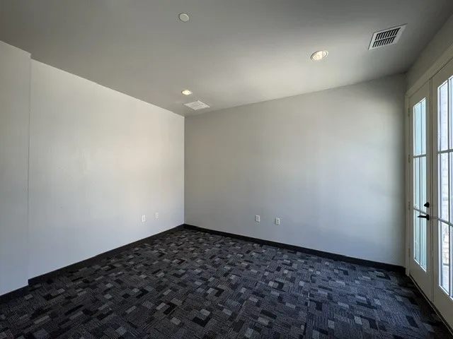 Recessed lighting, patterned carpet flooring, and a French door with multiple glass panes