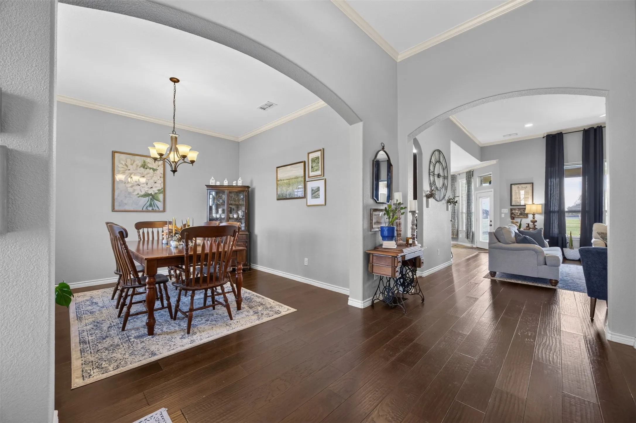 Dark wood-finish flooring throughout, framed arched doorways, recessed lighting, and crown molding