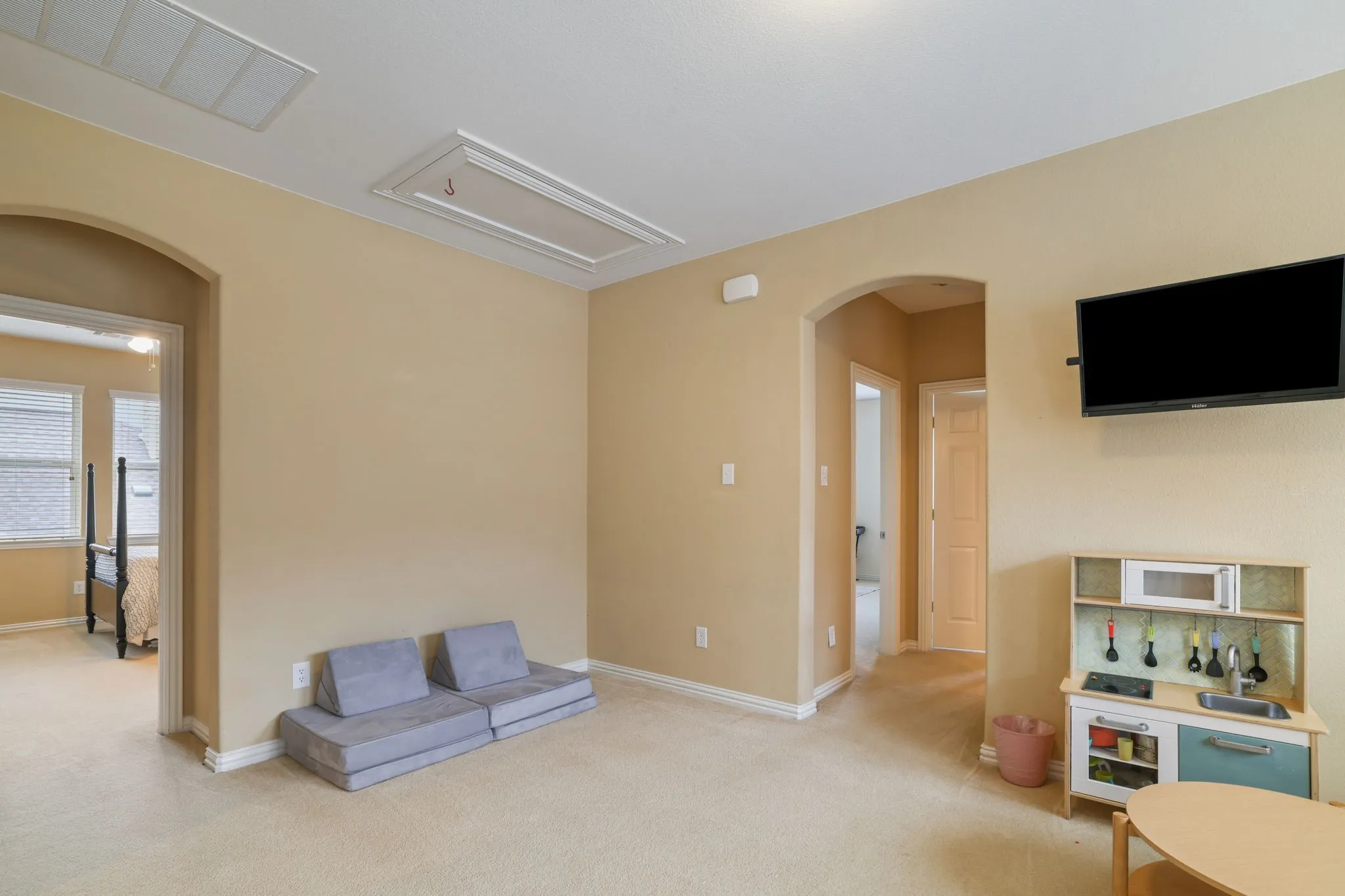 Carpeted room featuring neutral wall tones, arched doorways, and white trim