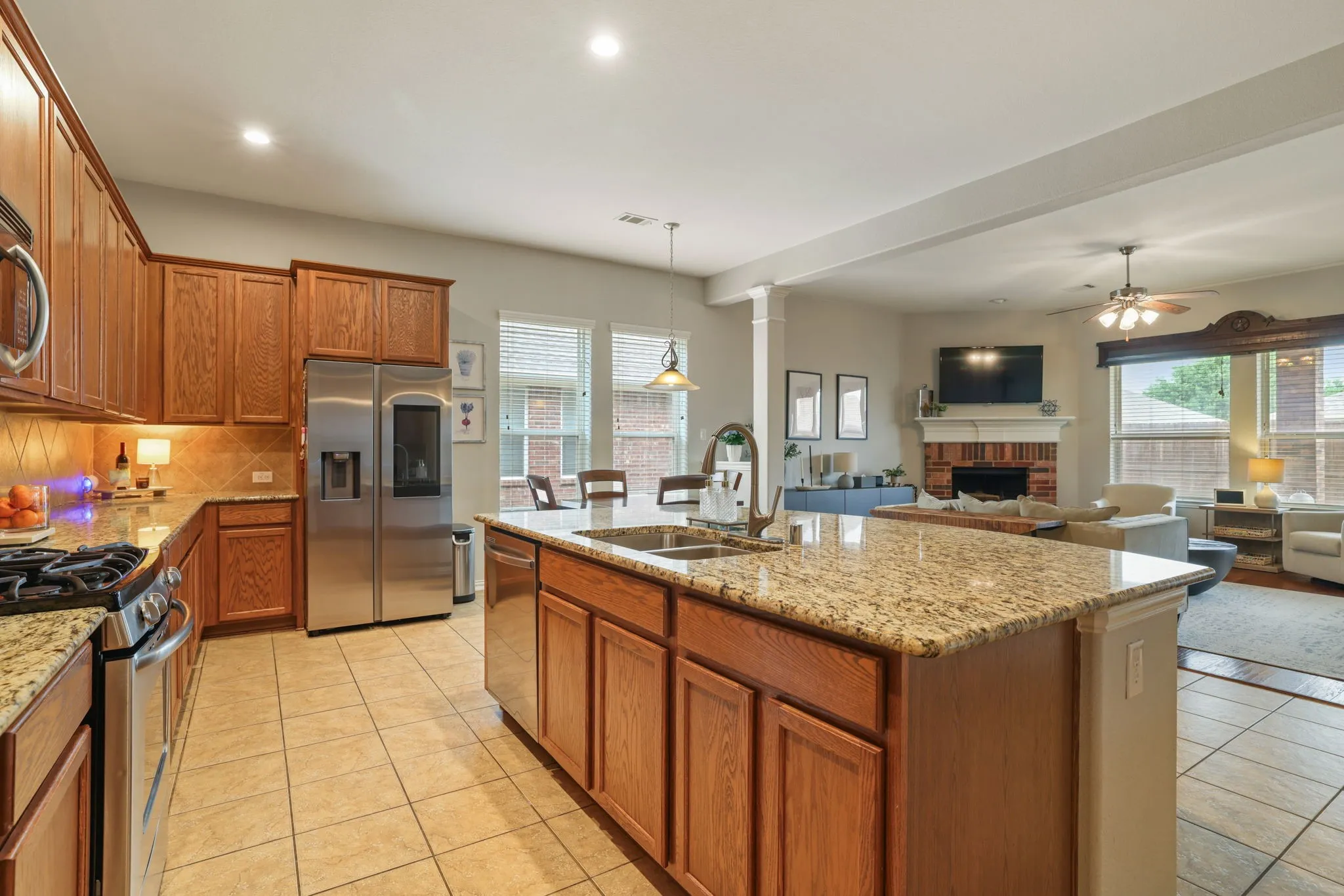 Kitchen featuring wood cabinetry, granite countertops, tile flooring, and stainless steel appliances