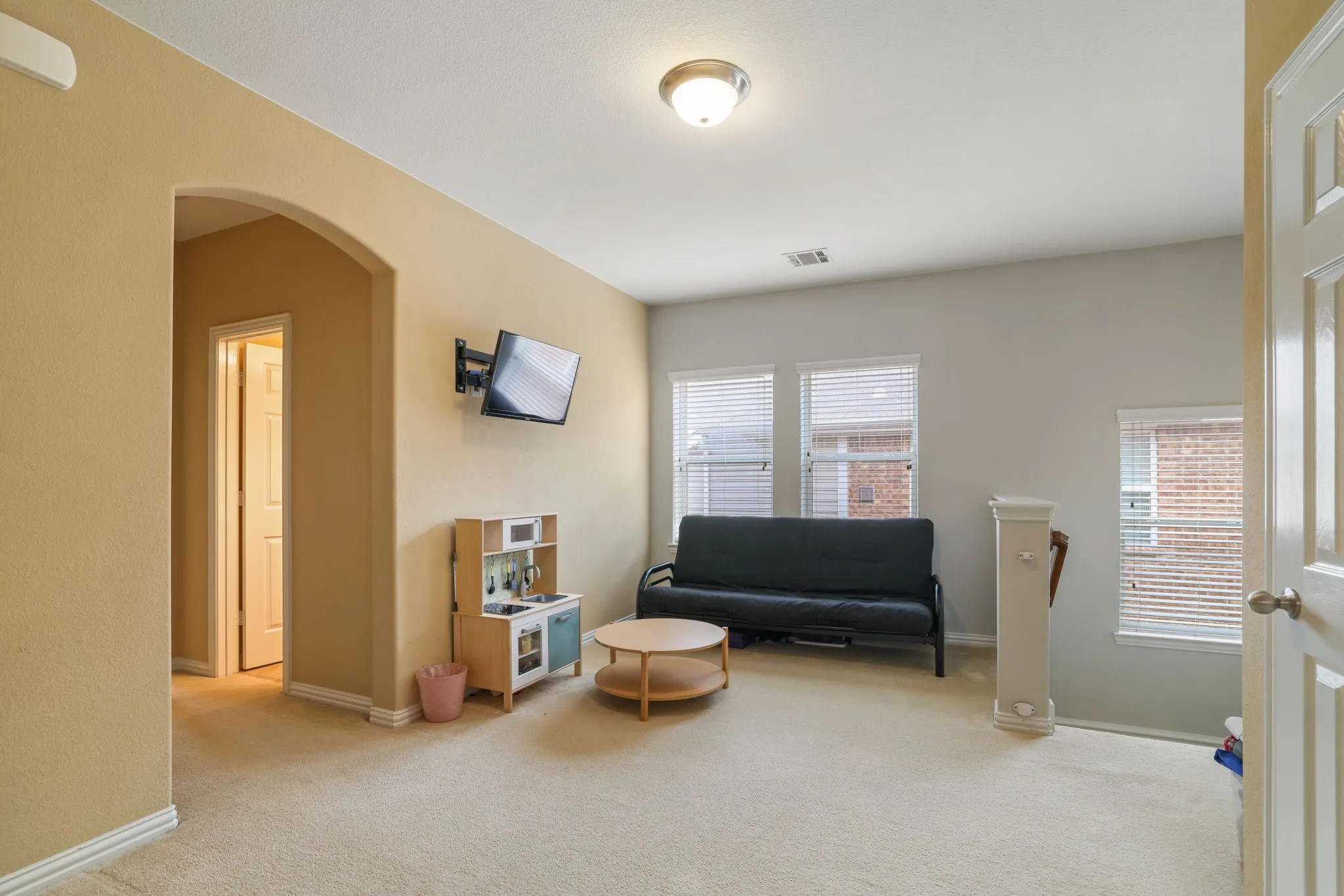 Carpeted room with multiple windows, an arched entryway, and neutral-toned walls