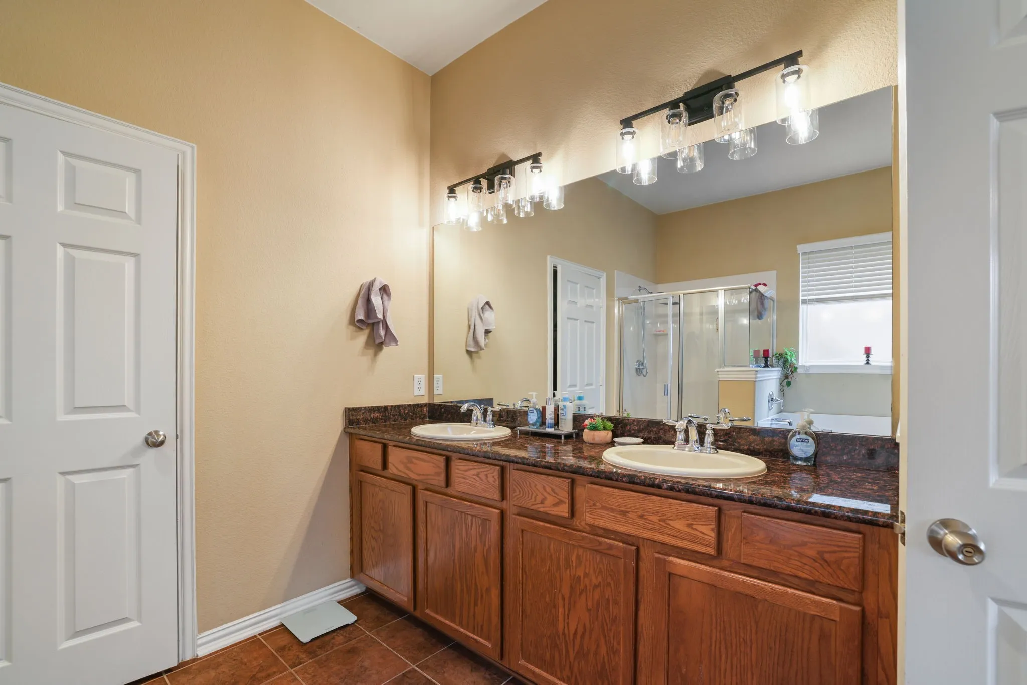 Double vanity with undermount sinks, stone-look countertop, and wood-finish cabinetry