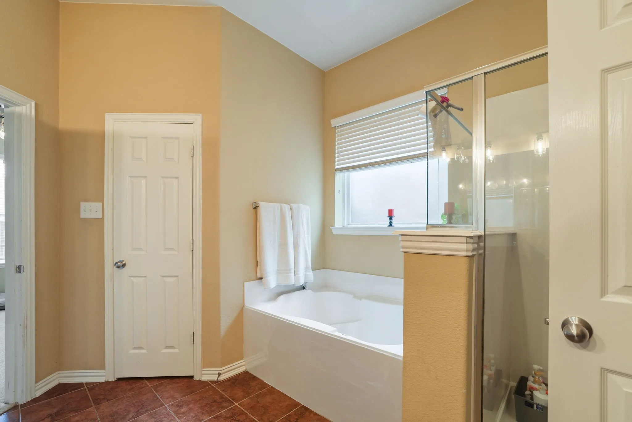 Built-in soaking tub with a window, glass-enclosed shower, and tiled flooring