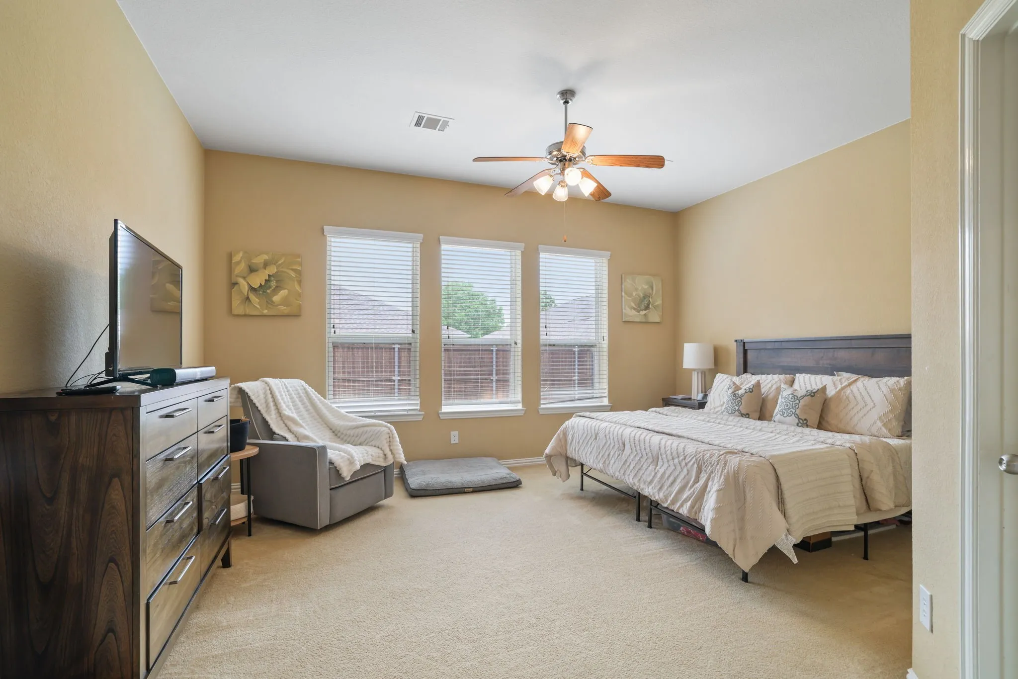 Vaulted ceiling with a ceiling fan, three windows with blinds, and carpeted flooring