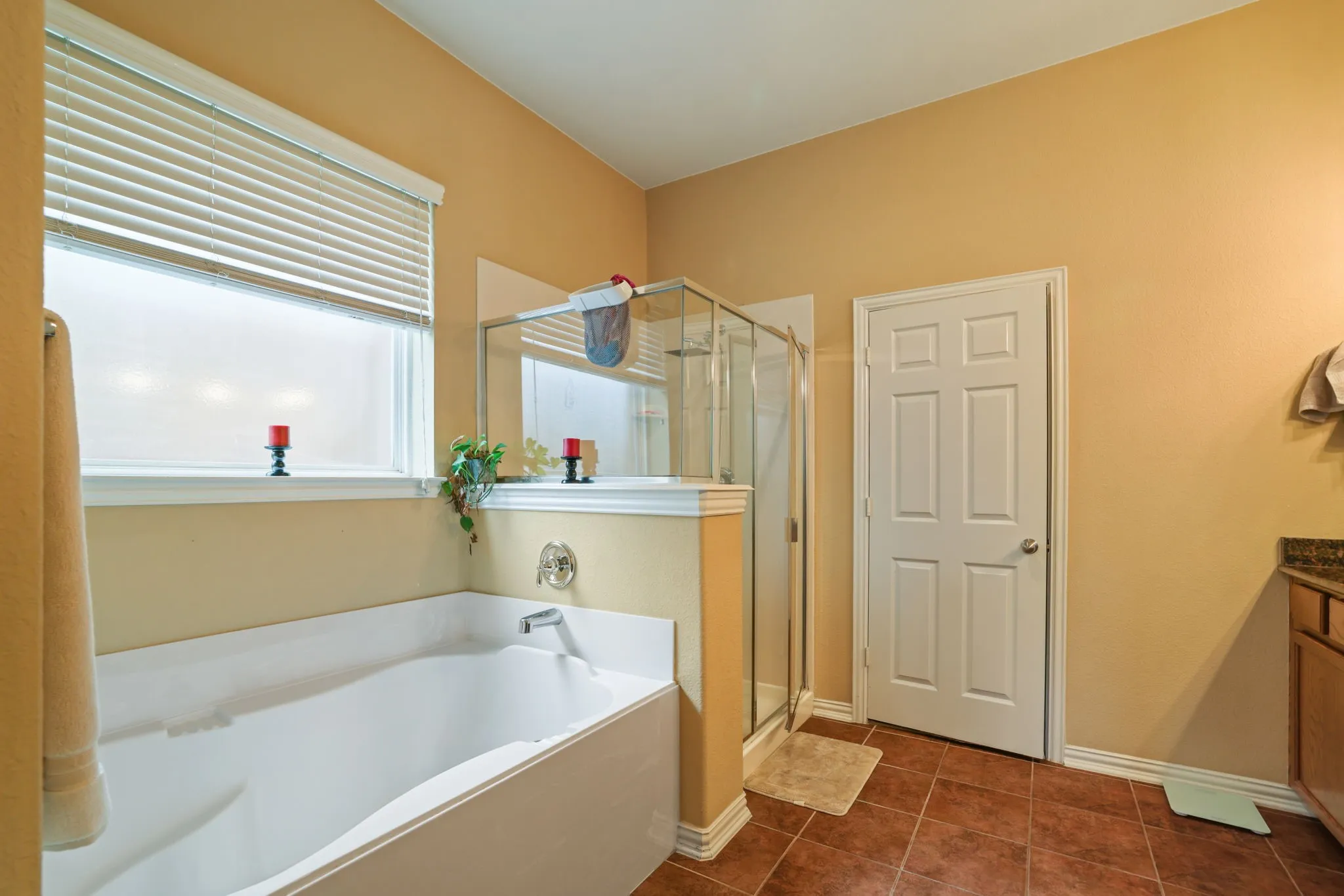 Soaking tub, enclosed glass shower, window with blinds, tile flooring, and a vanity with a stone countertop