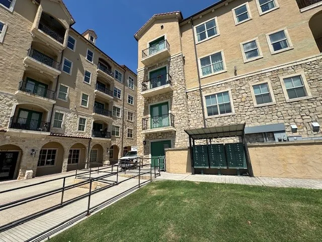 Stone and stucco exterior with multiple balconies, archways, and a paved walkway