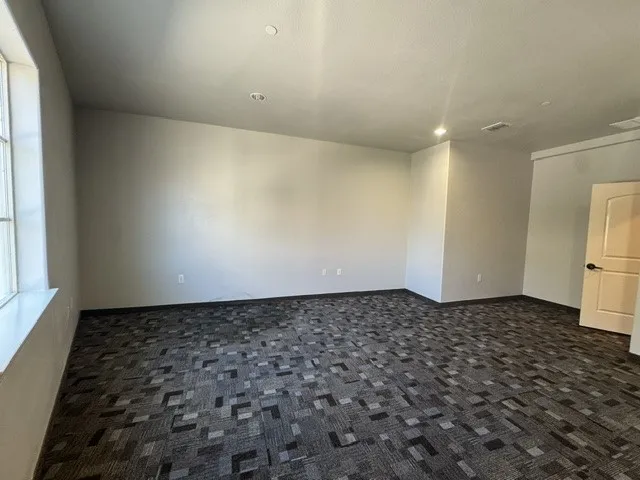 Recessed lighting, patterned carpeting, neutral wall finishes, and a light-colored interior door